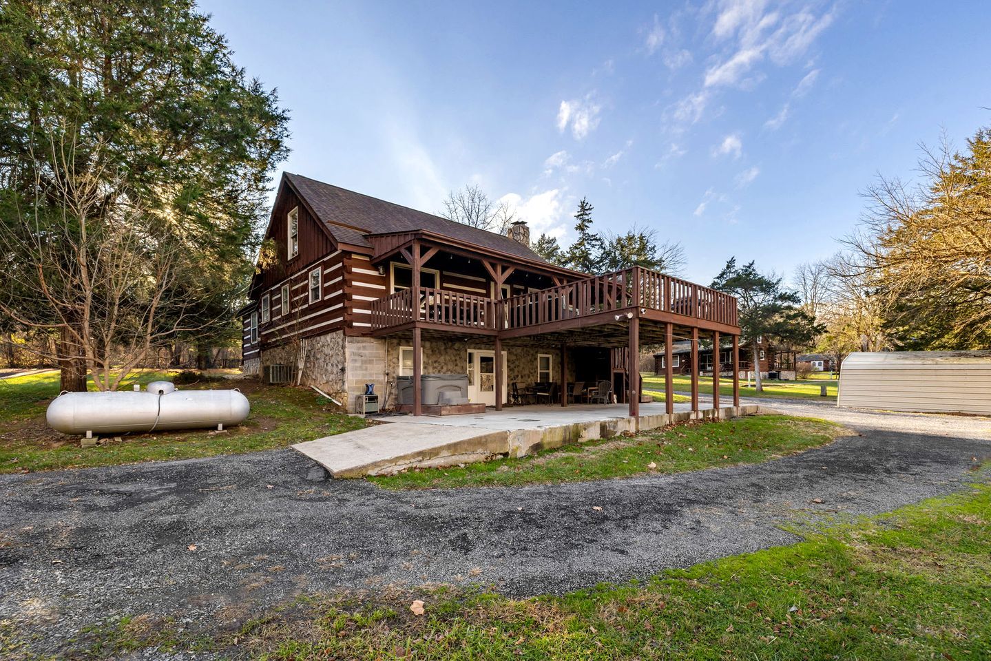 A two-story log cabin with a porch and a covered outdoor seating area.