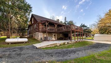 A two-story log cabin with a porch and a covered outdoor seating area.