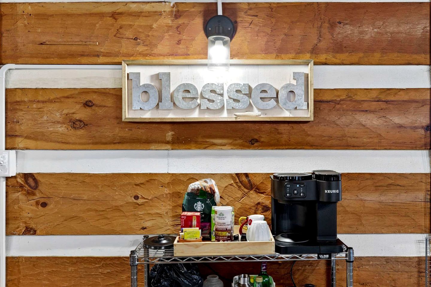 A coffee station with a sign that reads 'blessed' above it, a Keurig coffee maker, and various coffee pods and containers.