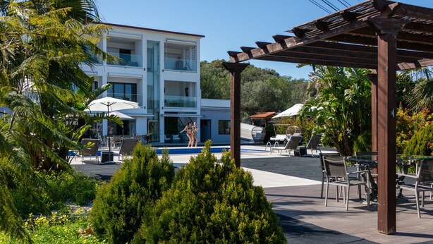 A modern building with a pool, outdoor seating, and lush greenery. - Vale Paraiso Relax Lounge (Olhao)