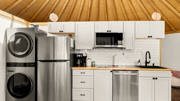 A compact kitchen with stainless steel appliances, white cabinetry, and a wooden ceiling.