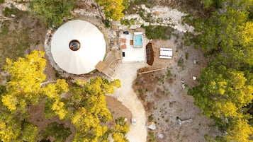 An aerial view of a property with a circular structure, a swimming pool, and a patio area.