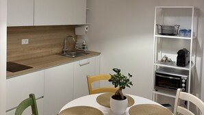 A modern kitchen with a wooden countertop, white cabinets, a sink, and a built-in oven. There is a dining table with chairs and a potted plant. - "Between Sky and Sea" Apartment in Pescara. Sea: 200 m. University 700 m.  Parking (Pescara)