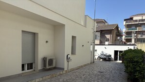 A paved courtyard with a motorbike, a closed shutter, and an air conditioning unit. - "Between Sky and Sea" Apartment in Pescara. Sea: 200 m. University 700 m.  Parking (Pescara)