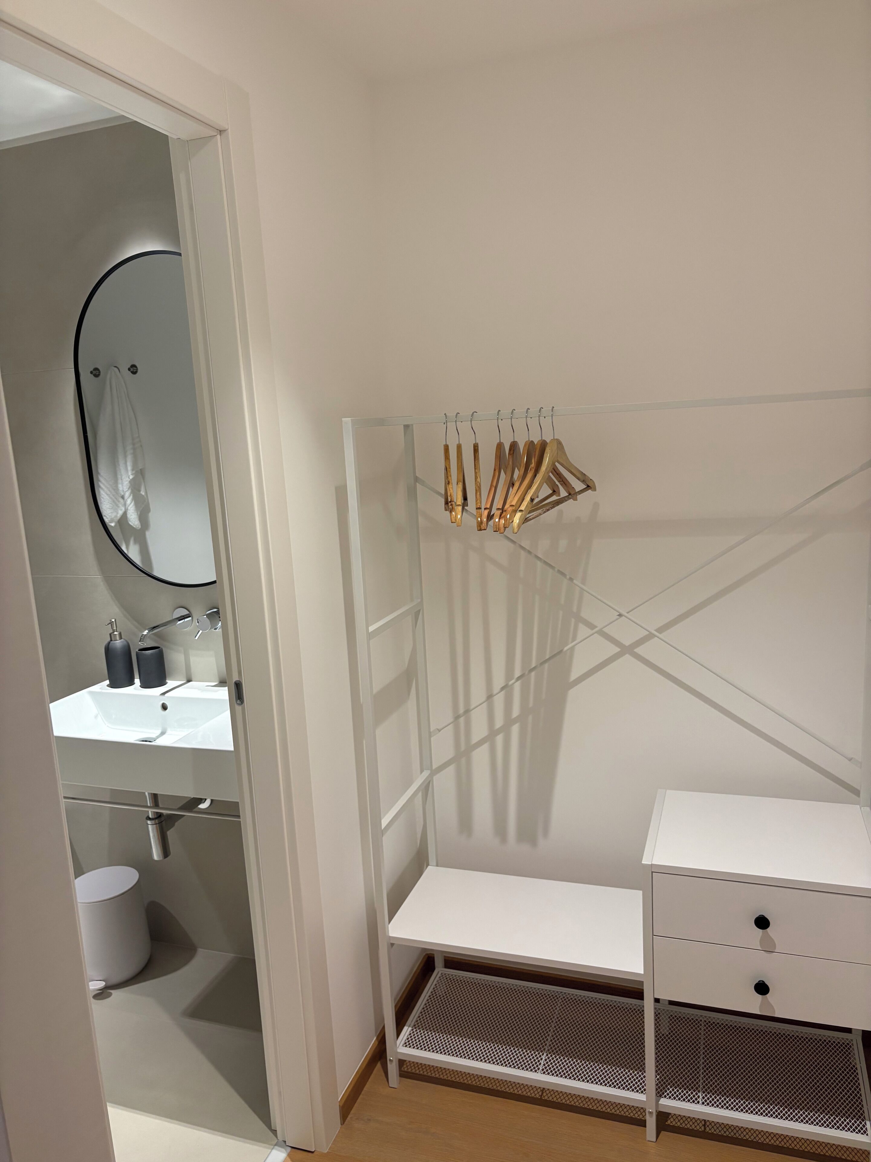 Un baño con lavamanos blanco, espejo y tocador blanco con cajones.
