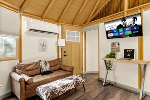 A cozy room with a brown leather couch, a wooden bench, a mounted TV displaying streaming services, and a welcome sign. - Luxurious Hill Country Yurt Cabin with Private Hot Tub Near Canyon Lake, Texas (Canyon Lake)
