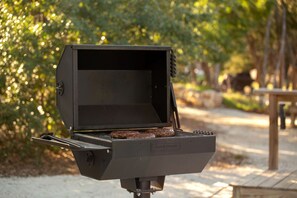 A portable grill with a flat cooking surface and a hinged lid, set outdoors with a natural backdrop. - Luxurious Hill Country Yurt Cabin with Private Hot Tub Near Canyon Lake, Texas (Canyon Lake)