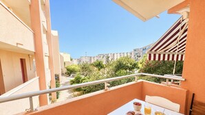 A balcony with a table set for breakfast, including croissants, fruit, and juice. - Cozy studio, pets and parking - 3 guests (Sète)