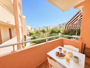 A balcony with a table set for breakfast, including croissants, fruit, and juice. - Cozy studio, pets and parking - 3 guests (Sète)