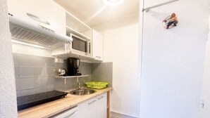 A compact kitchen with a microwave, stove, sink, and a small refrigerator. - Cozy studio, pets and parking - 3 guests (Sète)