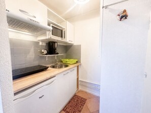 A compact kitchen with a microwave, stove, sink, and a small refrigerator. - Cozy studio, pets and parking - 3 guests (Sète)