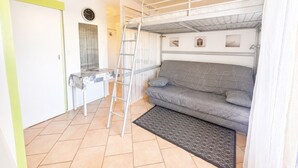 A compact room with a bunk bed, a small desk, and a sofa. - Cozy studio, pets and parking - 3 guests (Sète)