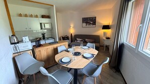 En kompakt opholdsstue med spiseplads, tekøkken og sofa.