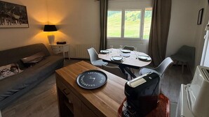 Et spiseområde med et bord dækket til fire personer, en kaffemaskine og et ur på et træbord.