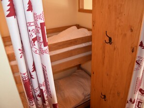 Un lit superposé avec une tête de lit en bois et une fenêtre au-dessus.