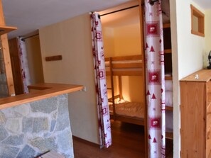 A cozy room with a bunk bed, a stone wall, and a wooden dresser. - Studio near slopes - 4 guests (Montgenèvre)