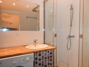 Ein modernes Badezimmer mit einem Holzbadezimmerschrank, einer Duschkabine aus Glas und einem eingebauten Geschirrspüler.