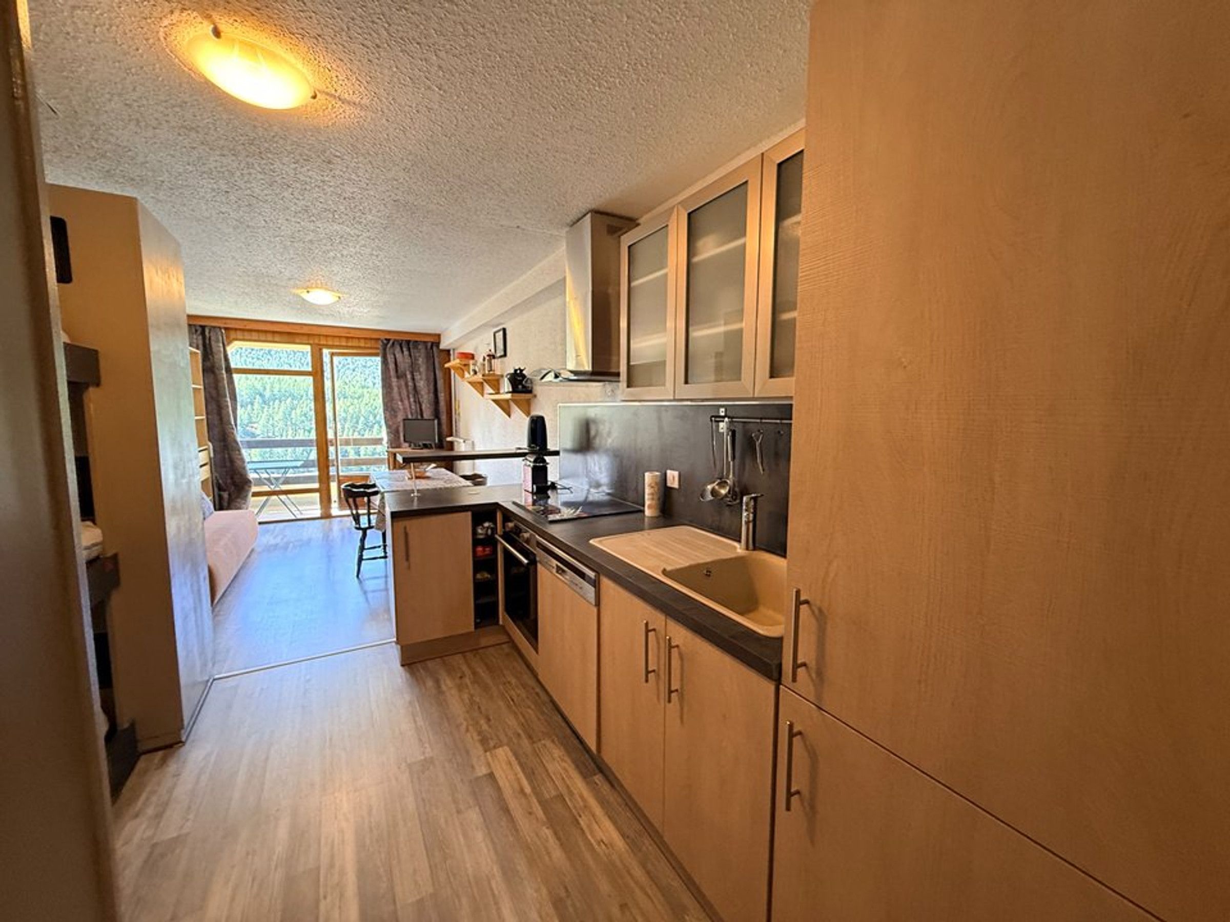 A compact kitchen with wooden cabinets, a sink, and a dining area with a table and chairs.