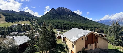 En bjerglandsby med traditionelle bygninger, en klar himmel og et markant bjerg i baggrunden.