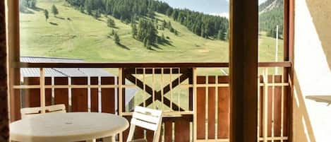 A balcony with a view of a green valley and forested hills.