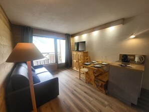 A compact room with a sofa, a dining table with chairs, a television on a cabinet, and a kitchenette area. - Studio with wifi - Piste view, 2 guests (Montgenèvre)