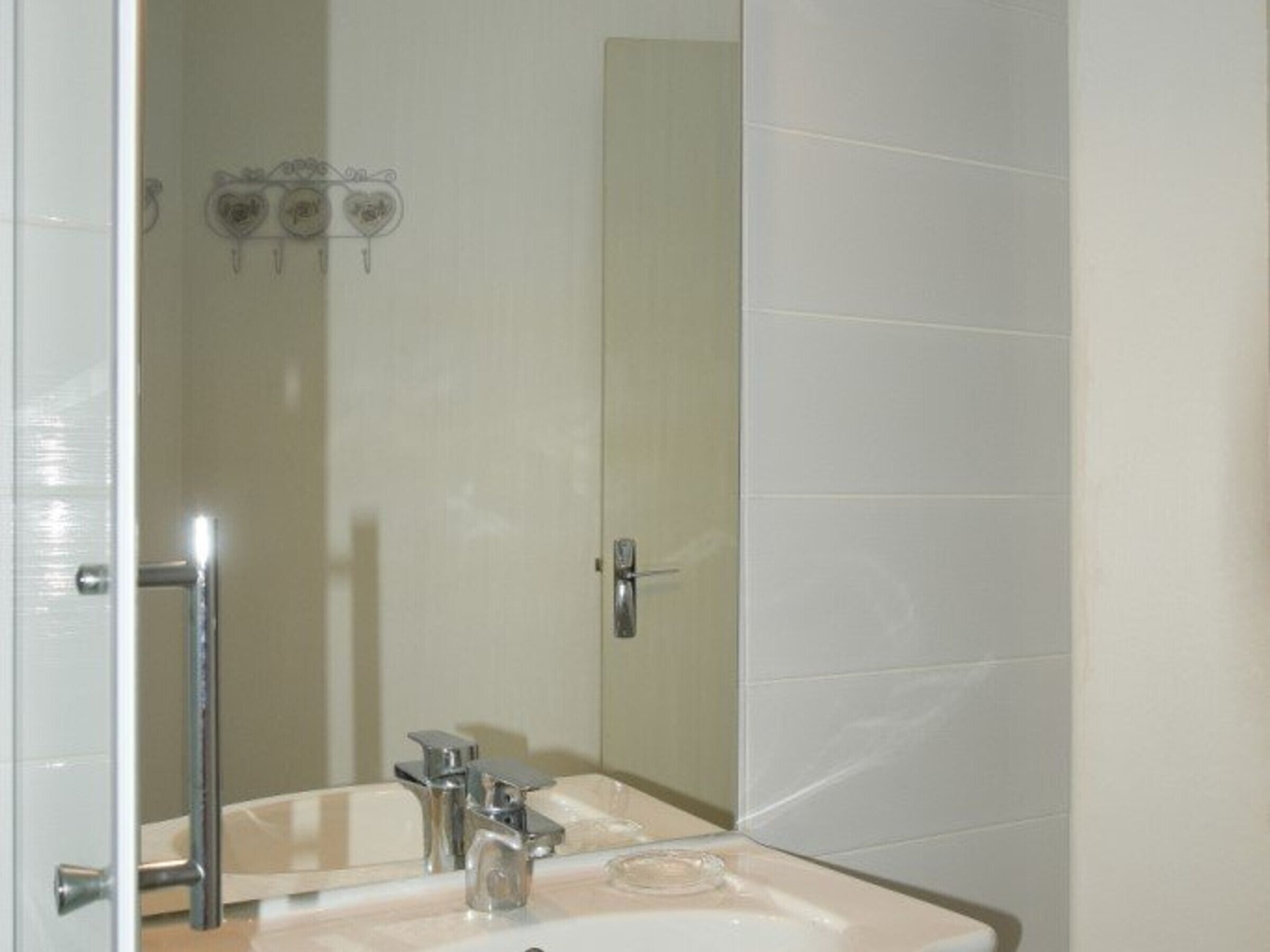 A bathroom with a sink, mirror, and towel rack.