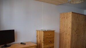 A room with a wooden dresser, a television, and a wardrobe. - Studio with pets allowed, parking - 4 guests (Montgenèvre)