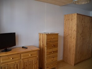 A room with a wooden dresser, a television, and a wardrobe. - Studio with pets allowed, parking - 4 guests (Montgenèvre)
