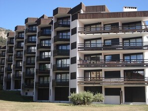 A row of modern multi-story residential buildings with balconies, white exteriors, and wooden accents. - Studio with pets allowed, parking - 4 guests (Montgenèvre)