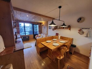 Ein Holztisch mit Stühlen, eine hölzerne Bank, ein Fenster mit Blick und ein Schild an der Wand.
