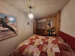 Un dormitorio con cama, un cartel en la pared, una lámpara colgante y un cabecero de madera.