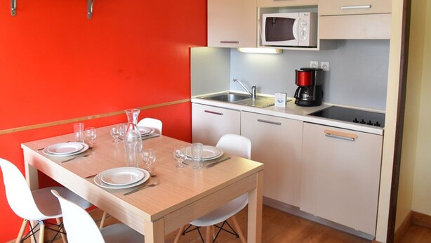 A compact kitchen with a microwave, coffee maker, and a sink. There is a dining table with chairs and a red accent wall. - Studio with pets allowed in Montgenèvre (Montgenèvre)