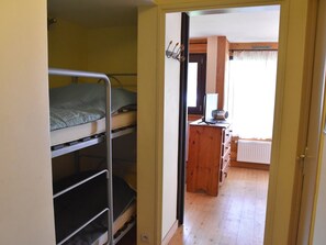 Ein Schlafsaalzimmer mit Etagenbetten, einer Holzkommode und einem Fenster mit Vorhängen.