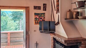 A room with a fireplace, a television mounted on the wall, and a door leading to a balcony. - Dolce Casa - Residence La Montanara (Camigliatello Silano)