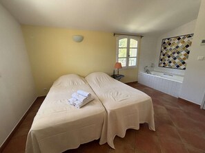 A room with two beds, a window, a lamp, and a bathroom with a tiled wall and a bathtub. - Apartment sea view - 6 guests (Saint-Cyr-sur-Mer)