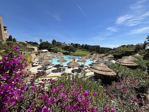 A pool area with lounge chairs and umbrellas, surrounded by greenery and buildings. - Apartment sea view - 6 guests (Saint-Cyr-sur-Mer)