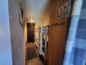 A narrow hallway with bunk beds, a door, and a poster on the wall. - Studio at the foot of the slopes - 4 guests (Montgenèvre)