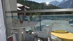 Ein Balkon mit Tisch und Stühlen, mit Blick auf einen Parkplatz und Berge.