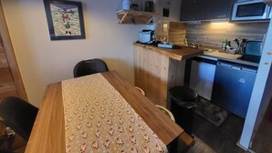 Eine kompakte Küche mit Holztischplatte, einer eingebauten Mikrowelle und einem kleinen Spülbecken.