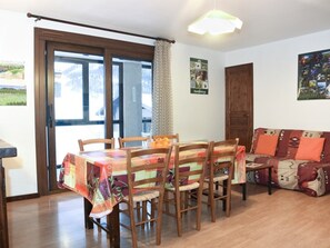 A dining area with a table and chairs, a sofa, and a door. - Cozy central apartment - 5 guests (Montgenèvre)