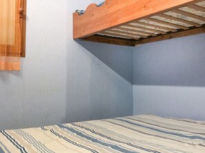 Un dormitorio con literas, una ventana con cortina y una colcha estampada.