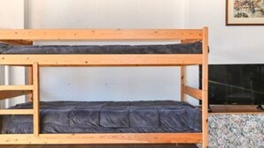 A bunk bed with a lower bunk and a mattress, a wooden headboard, and a framed picture on the wall. - Studio with parking, pets OK, mountain view (Montgenèvre)