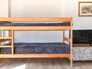 Ein Etagenbett mit unterem Bett und einer Matratze, einem hölzernen Kopfteil und einem gerahmten Bild an der Wand.