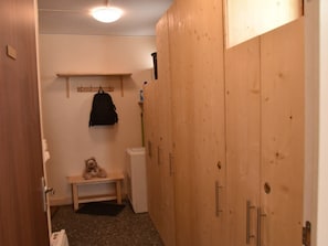 Ein kleiner Raum mit Holzausstattung, einer Sitzbank und einem Kleiderständer.