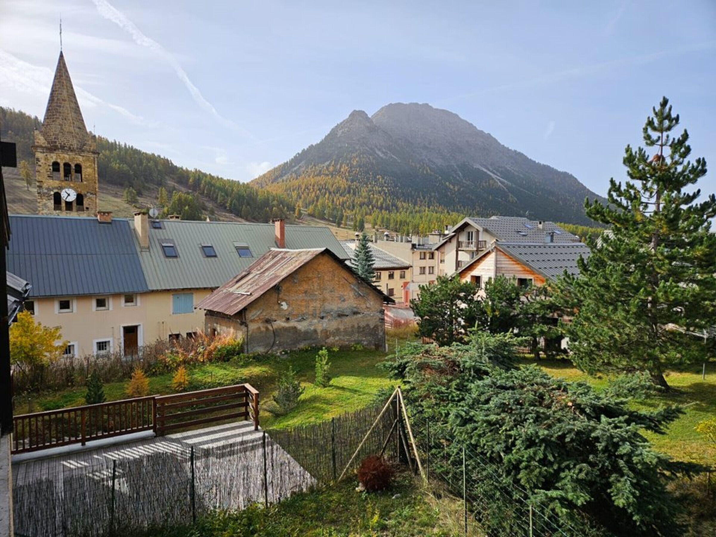 A village with traditional buildings, a church tower, and a mountain in the background.