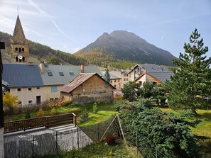 Ein Dorf mit traditioneller Bebauung, einem Kirchturm und einem Berg im Hintergrund.