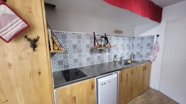 A kitchen with a wooden countertop, a white dishwasher, and patterned backsplash tiles. - Studio in the village center with wifi - 4 guests (Montgenèvre)