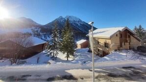 A snow-covered mountain with a clear sky, a wooden cabin, and a building with a sloped roof. - Studio in the village center with wifi - 4 guests (Montgenèvre)