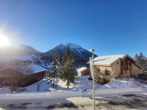 Ein mit Schnee bedeckter Berg, ein klarer Himmel, eine Holzhütte und ein Gebäude mit einem geneigten Dach.