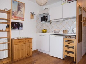 A compact kitchen with white cabinets, a microwave, a small sink, and a wooden cabinet with drawers. - Studio in Montgenèvre center - 3 guests (Montgenèvre)